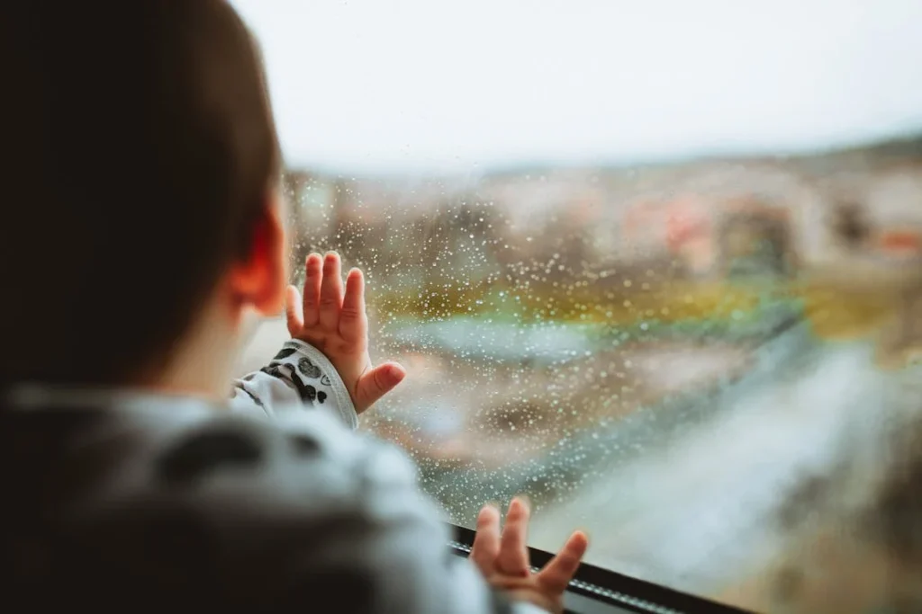 petit enfant avec la main sur une fenêtre sale